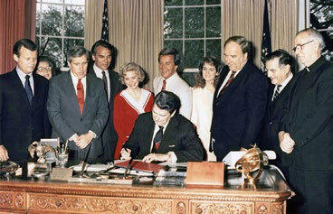 President Ronald Reagan signing Public Law 100-307 on 5 May 1988